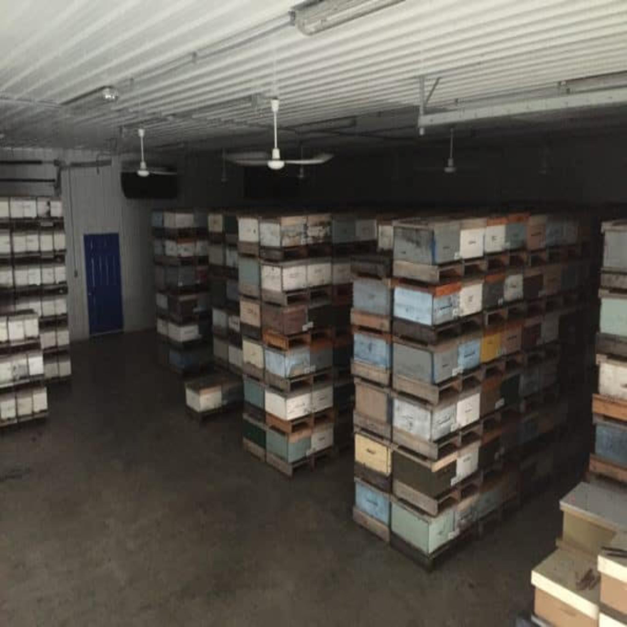 Storage room with stacked pallets and boxes on metal shelves.